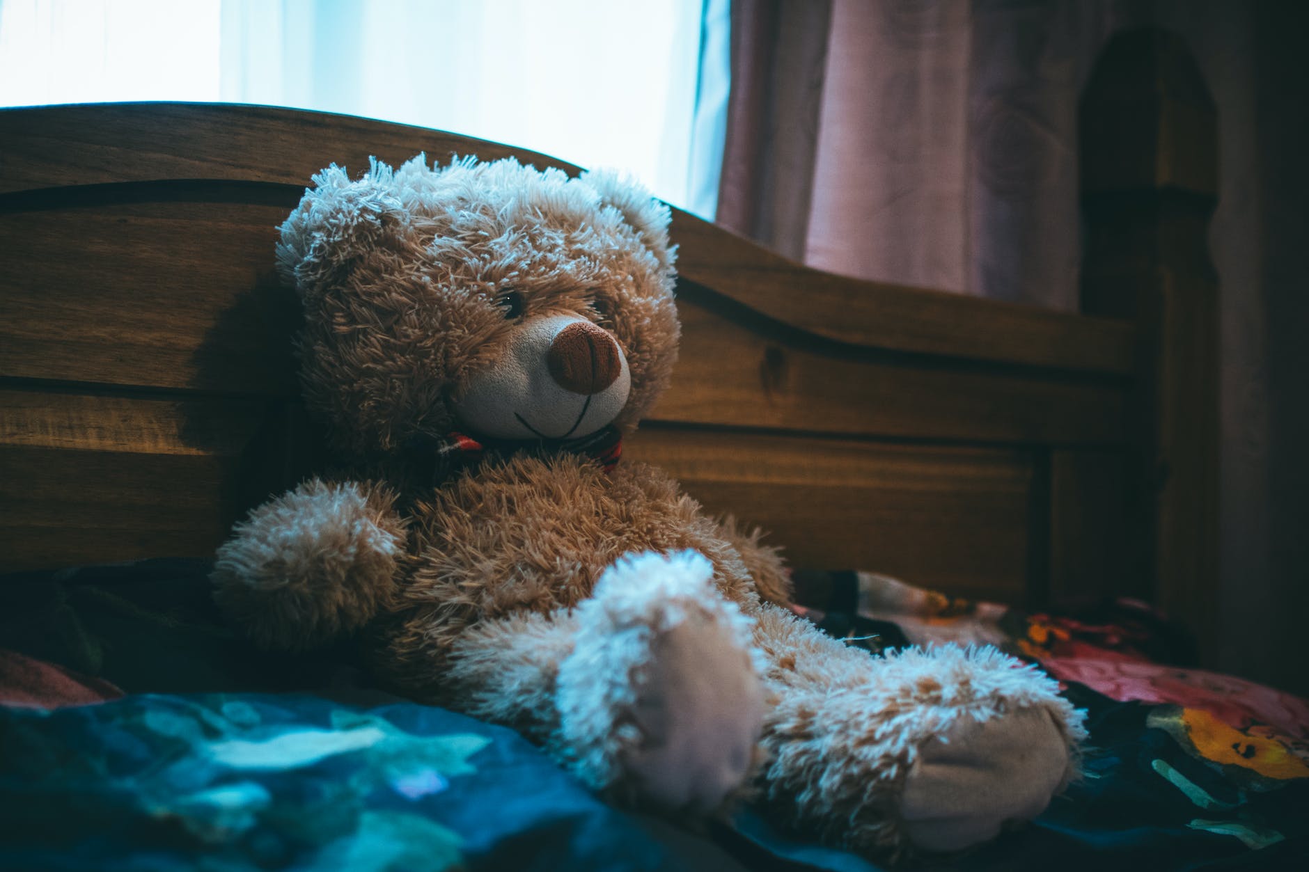brown bear leaning on bed headboard