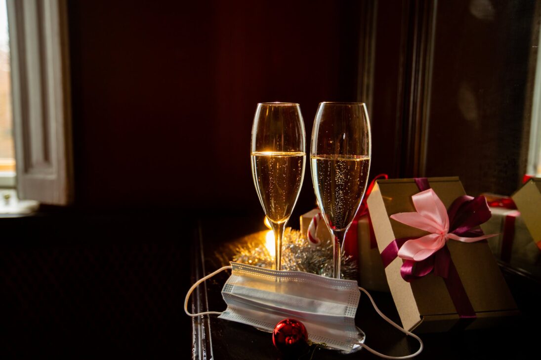 champagne glasses on table with gifts and face mask