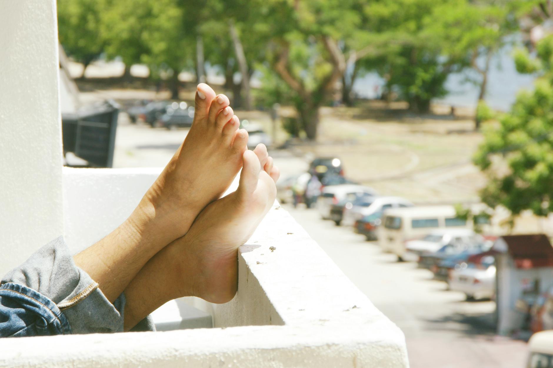 person wearing blue denim jeans with feet on railings