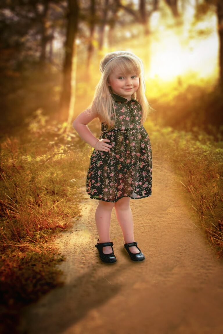 girl in black and pink floral sleeveless dress stands in pathway