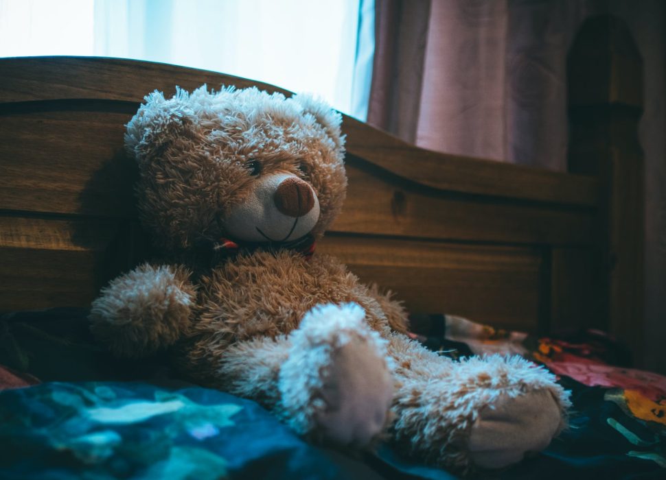brown bear leaning on bed headboard